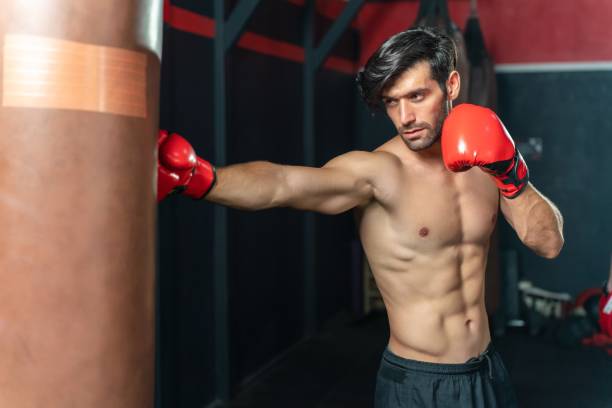 Photo of a young and handsome boxer with muscular build body with red gloves training in a gym